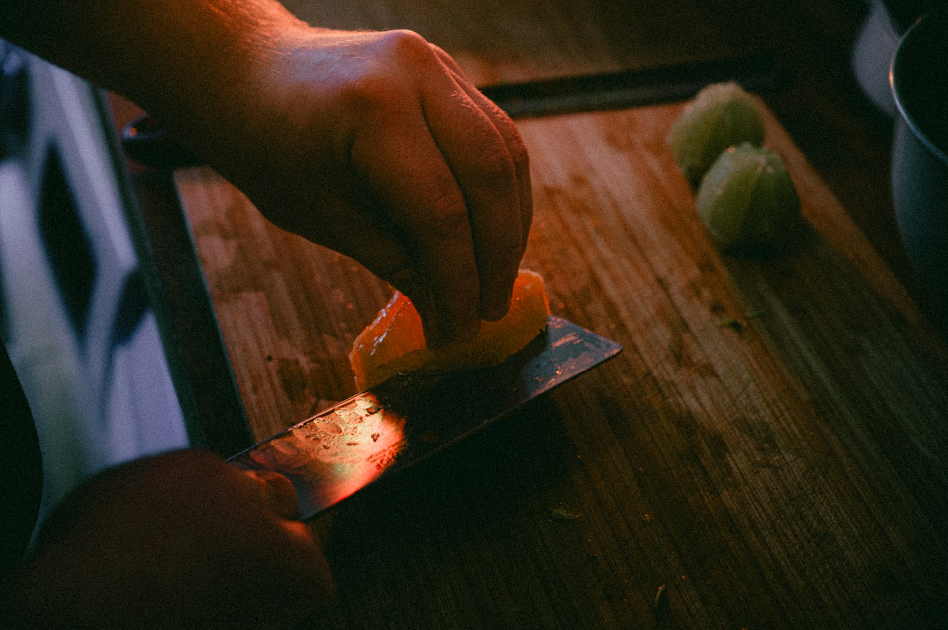 a person slicing an orange on a cutting board